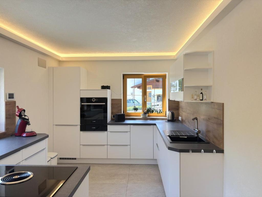 uma cozinha com armários brancos e um aparelho preto em Apartment Panoramablick by Interhome em Weissenbach am Lech