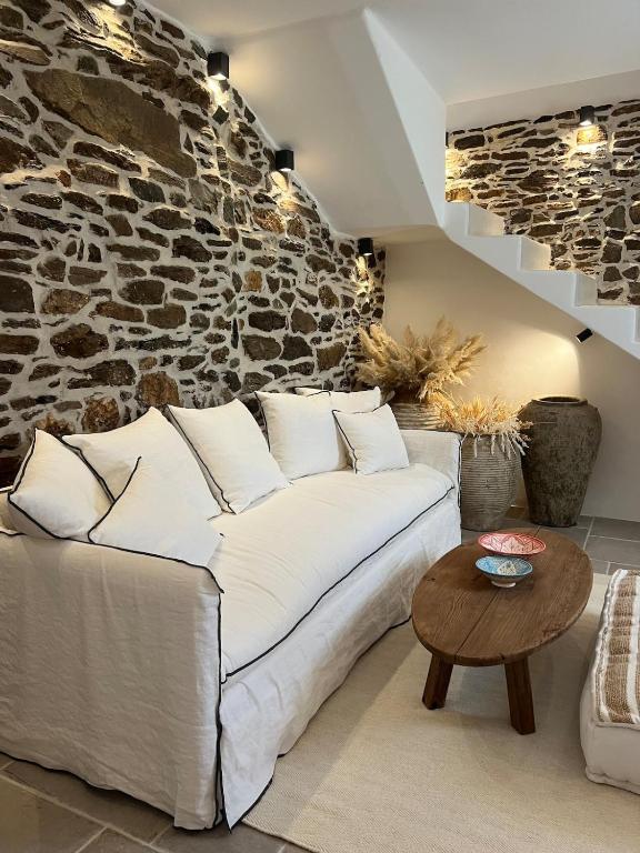 a living room with a white couch and a stone wall at Estrella house in Kithnos