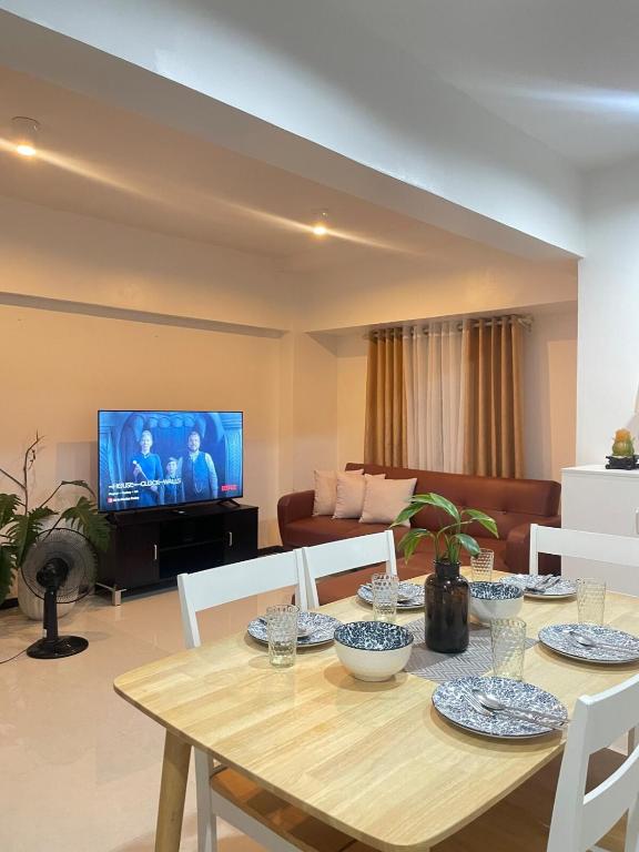 a living room with a wooden table and a television at Affordable Family Loft Condo near Mactan Airport by A&C in Mactan Cebu International