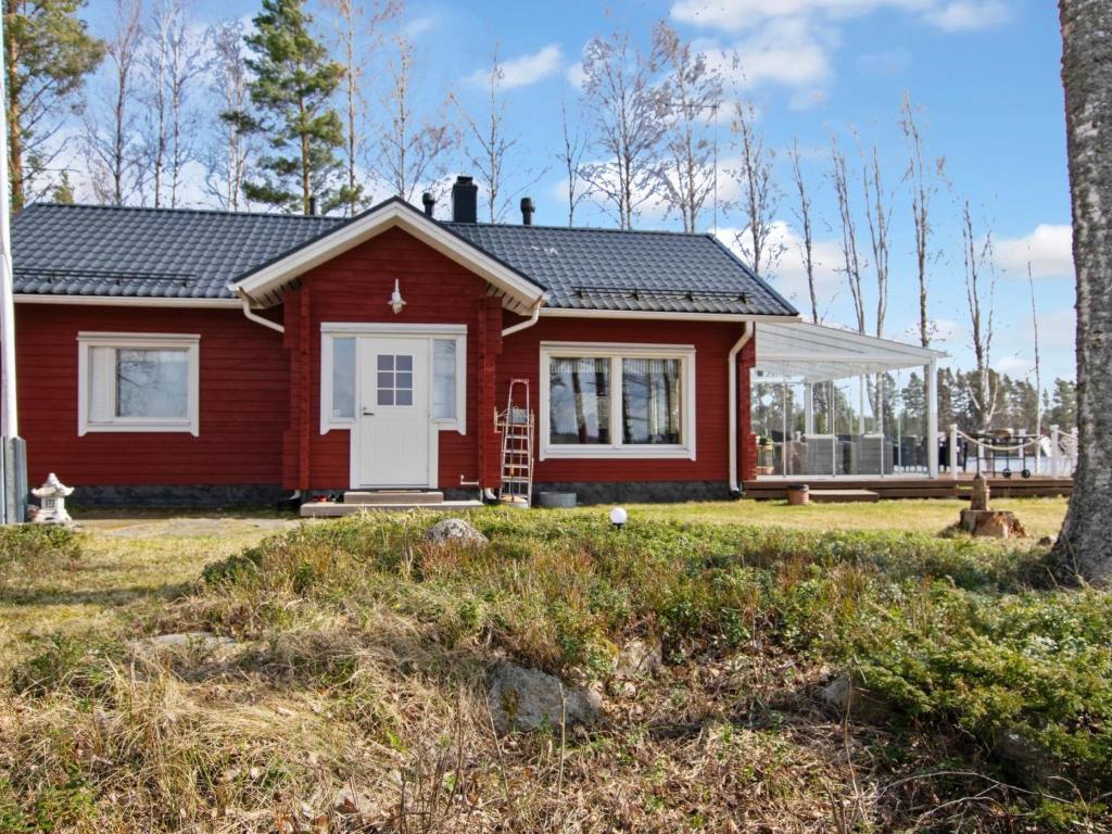 a red house with a white door in a yard at Holiday Home Kesäranta by Interhome in Alavus