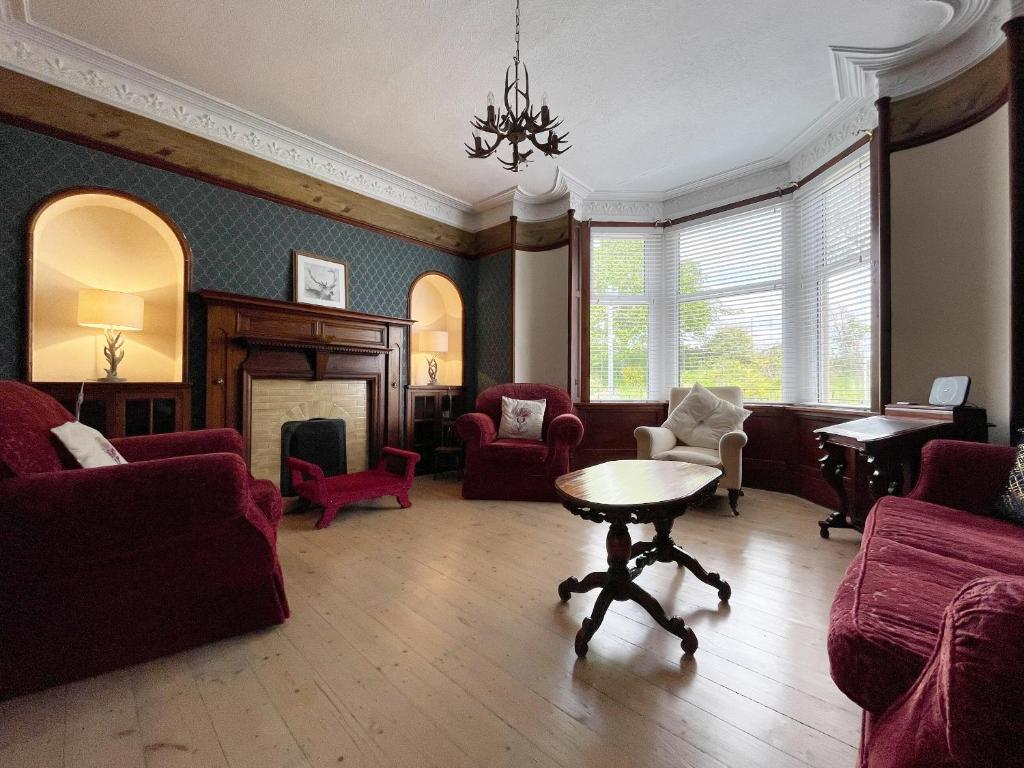 a living room with red chairs and a table at Stanford House in Inverness