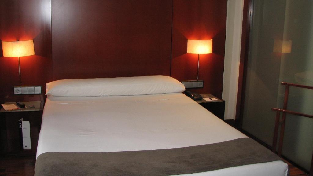 a bed in a small room with two lamps at Zenit Málaga in Málaga