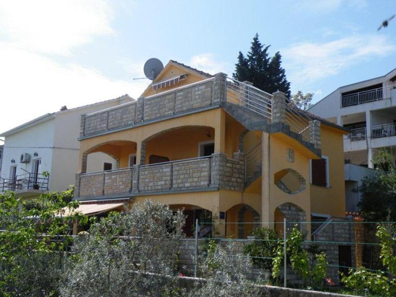 a yellow building with a balcony on top of it at Apartmani Štulec in Preko