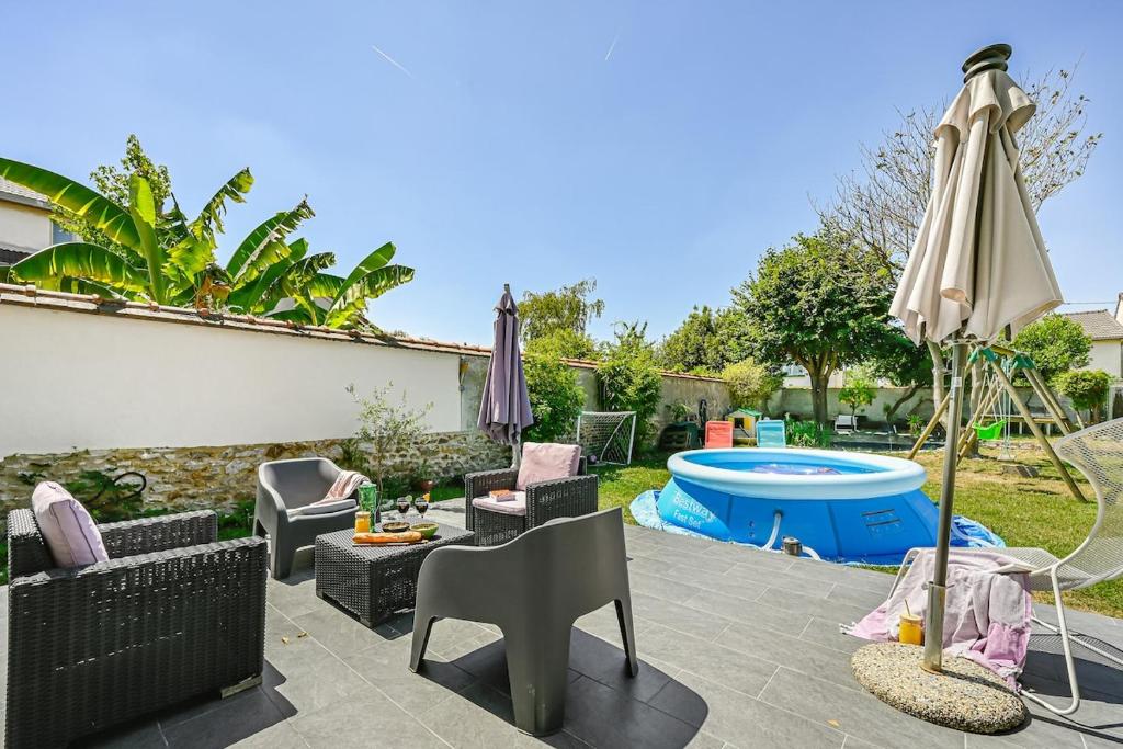 une terrasse avec des chaises et un parasol ainsi qu'une piscine dans l'établissement La belle escale entre Paris et Disney, à Le Perreux-Sur-Marne