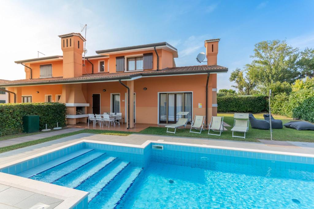a villa with a swimming pool in front of a house at Villa Quadrilocale V4P in Isola Albarella