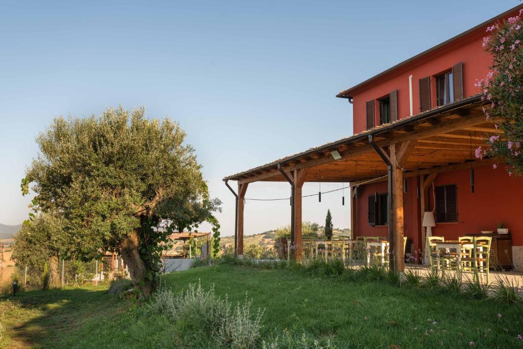 a red house with a table and a tree at Il Giardino di Elena in Montiano