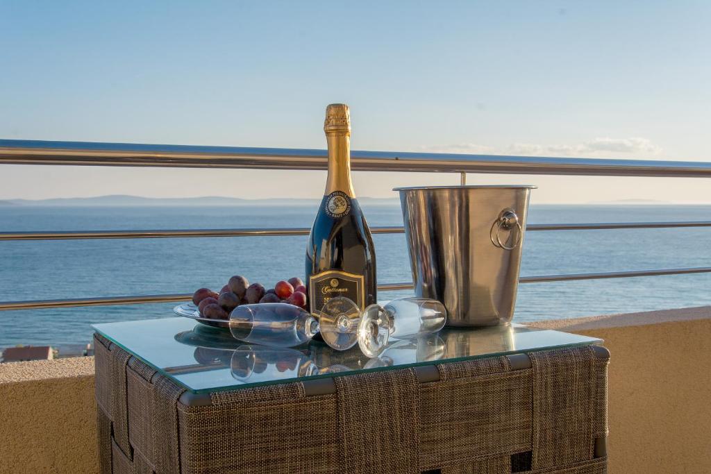 uma garrafa de vinho e uma taça de uvas numa mesa em Apartments Max&Leon em Podstrana
