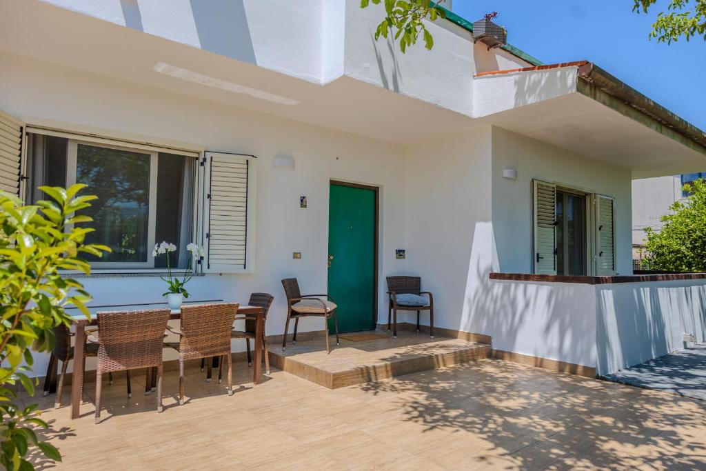 a patio with chairs and a table and a green door at Casa Carmen in Stazione di Paestum