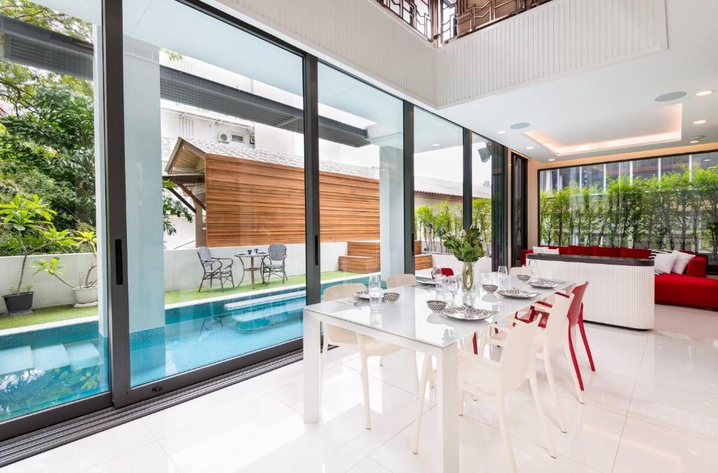 ein Esszimmer mit einem weißen Tisch und Stühlen sowie einem Pool in der Unterkunft Modern Luxury Poolhaus with Lift in Klong Toi