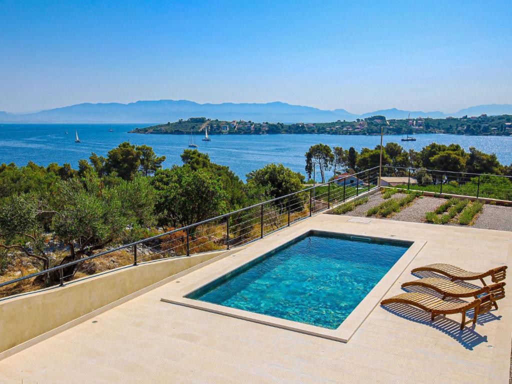 a swimming pool on a patio with a view of the water at Holiday Home Sova by Interhome in Nečujam