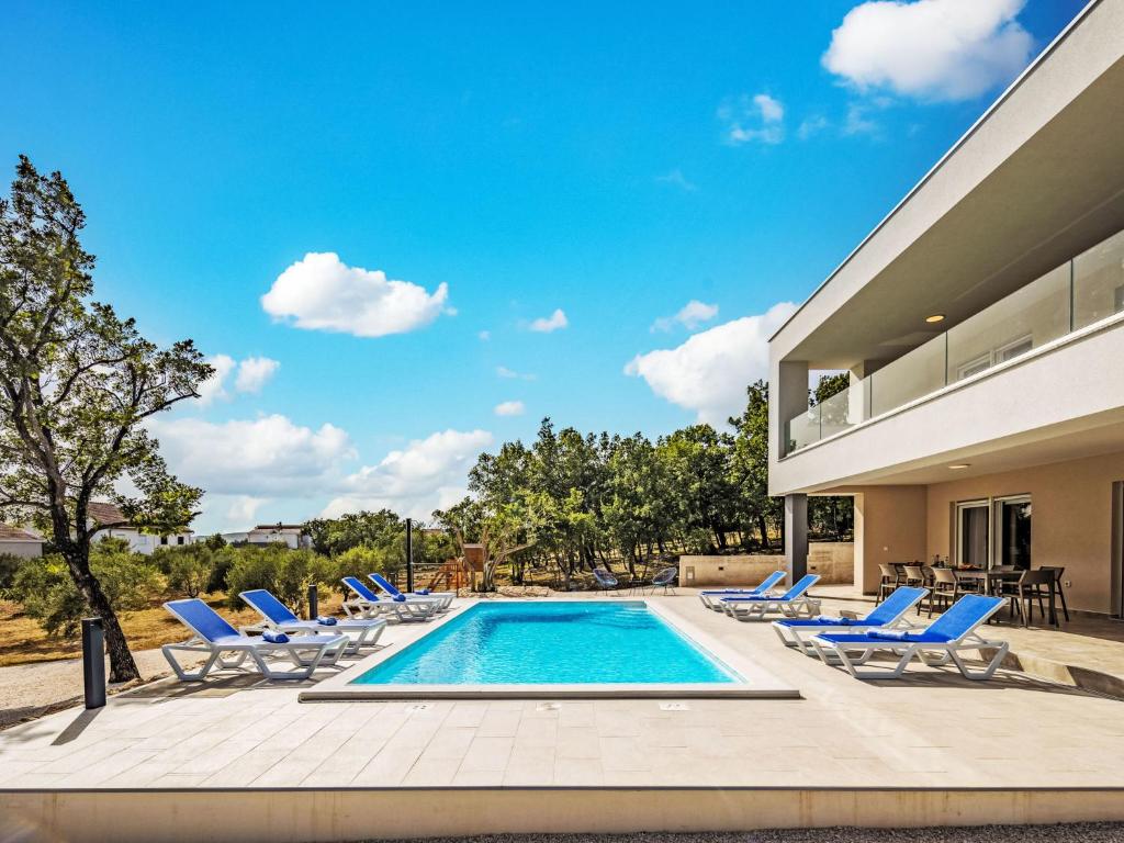 Una piscina con tumbonas y una casa. en Villa Green & Blue by Interhome, en Maslenica