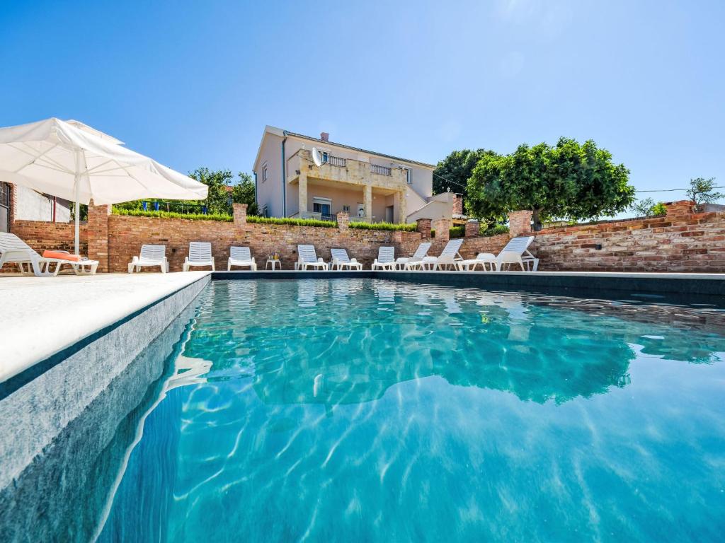 una piscina con sillas y sombrilla en Holiday Home Villa Meri by Interhome, en Benkovac