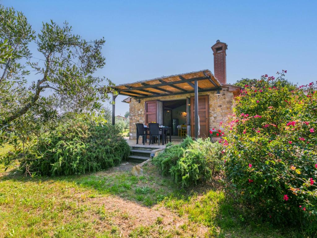a stone house with a porch with chairs and flowers at Holiday Home Rustico by Interhome in Bibbona