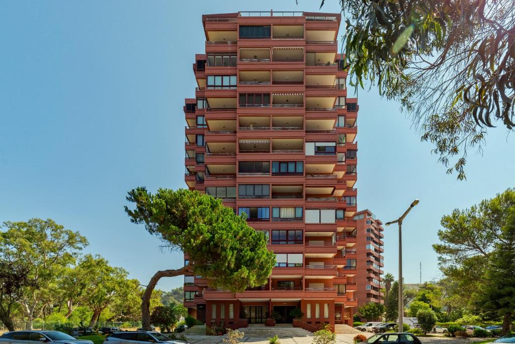 a tall building with a tree in front of it at Regina Beach House - By Y Concept in Costa da Caparica