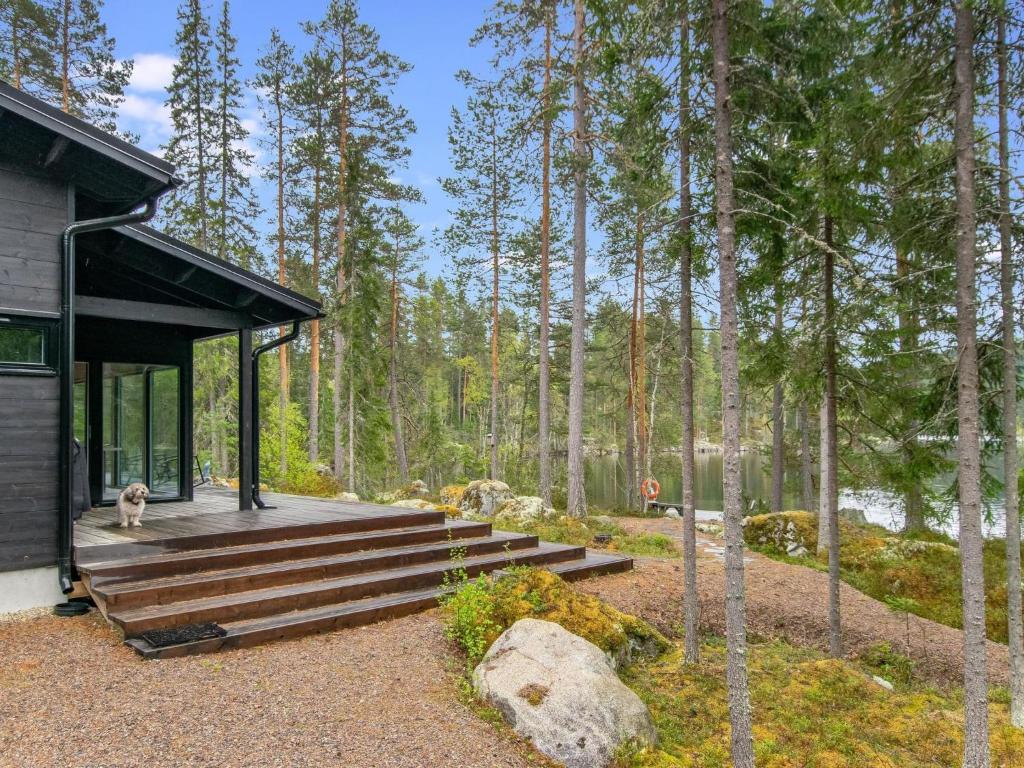 a dog sits on the porch of a cabin in the woods at Holiday Home Sarppala by Interhome in Putkijärvi