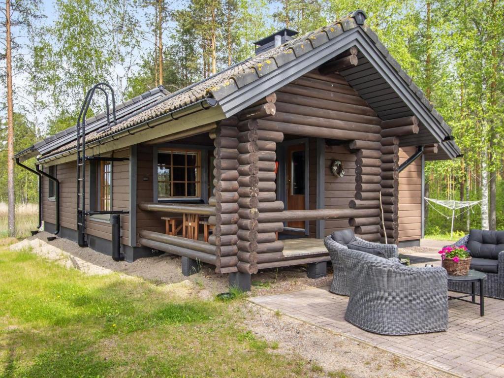 a log cabin with a porch and a table and chairs at Holiday Home Mustijoki by Interhome in Savitaipale