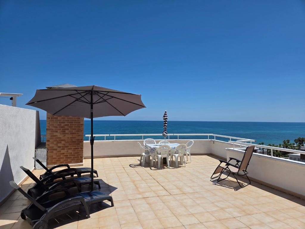a patio with a table and chairs and an umbrella at acapulco 3 frontal in Oropesa del Mar