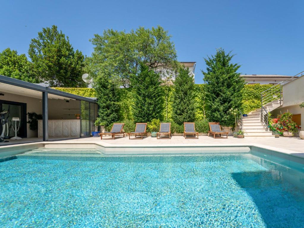 a swimming pool with chairs and a house at Apartment Dita-1 by Interhome in Crikvenica