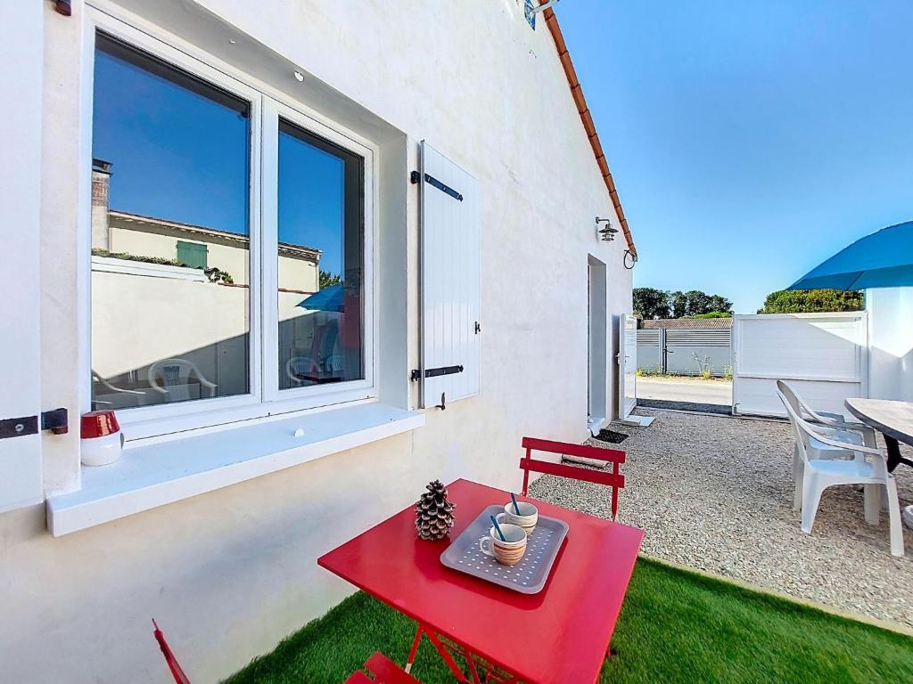a red table and a red bench in a yard at Holiday Home Maison du bois by Interhome in Les Mathes