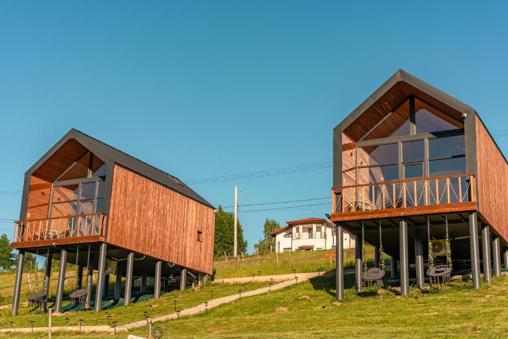 zwei Holzgebäude mit großen Fenstern auf einem Feld in der Unterkunft Suspended Tiny House in Drumu Carului