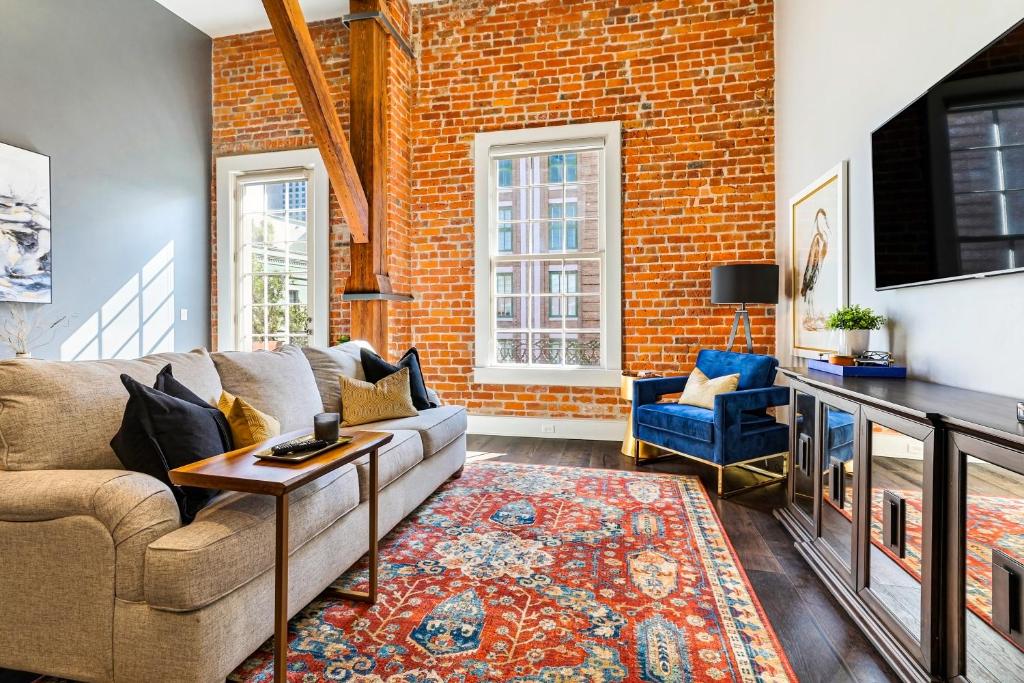 Una sala de estar con un sofá y una pared de ladrillos. en New Orleans Luxury Rentals - The Rex, en Nueva Orleans