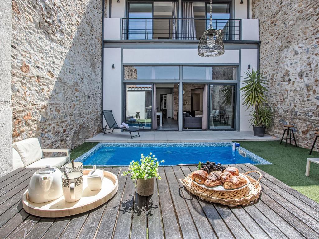 a patio with a table with a basket of food next to a pool at Holiday Home La Grange by Interhome in Torreilles