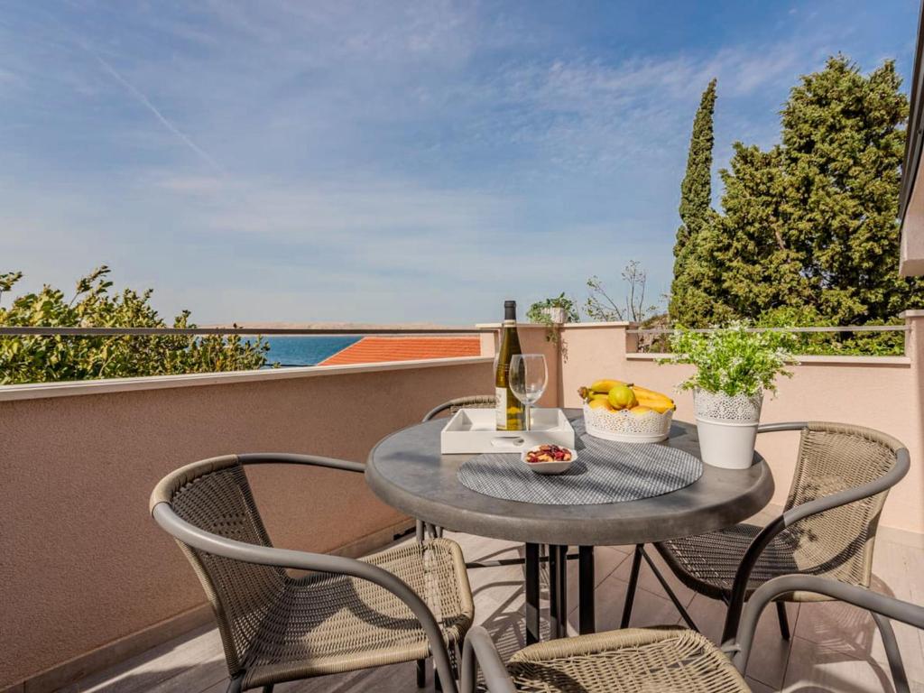 een tafel met een fles wijn en fruit op een balkon bij Apartment Sofija-2 by Interhome in Karlobag
