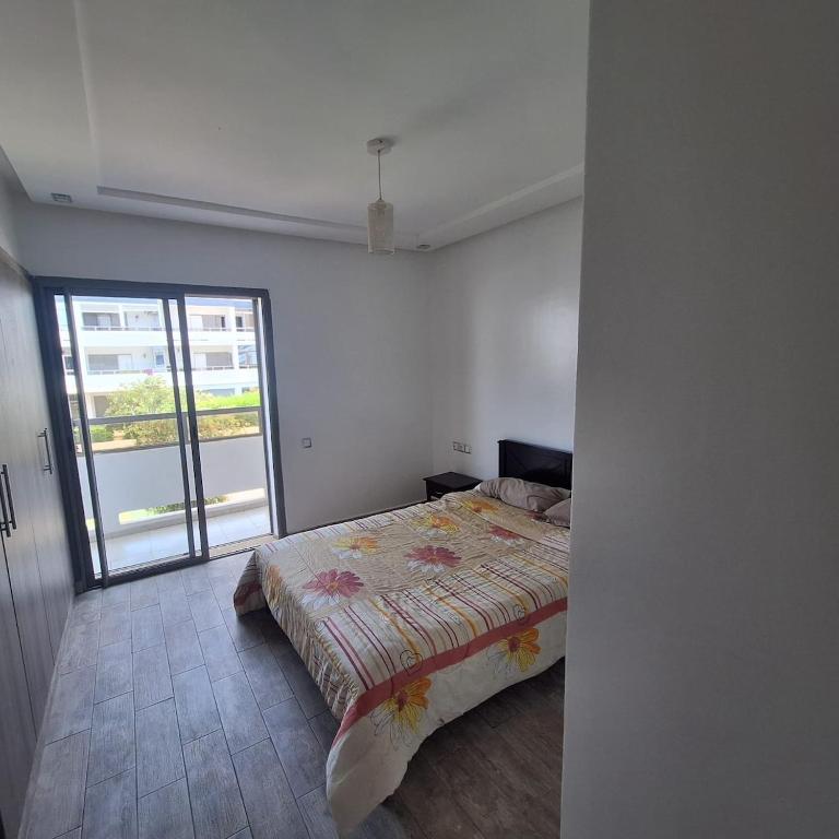 a bedroom with a bed and a large window at Appartement marbella beach in Mansouria