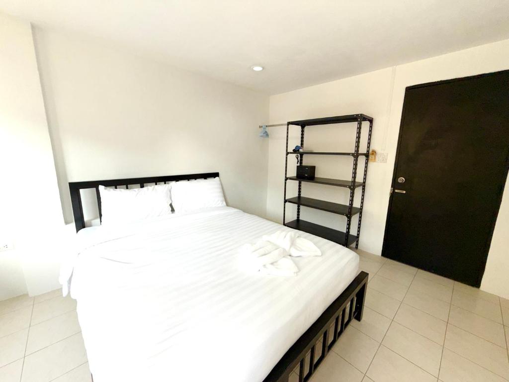 a bedroom with a bed with white sheets and a black door at Patong Canal Villa R203 in Patong Beach
