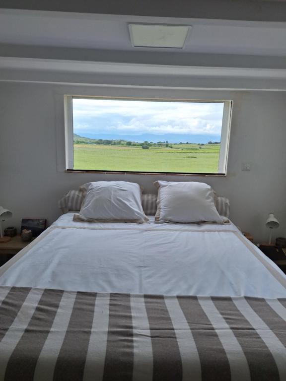 a bedroom with a large bed with a large window at Duplex piscine calme in Vendémian
