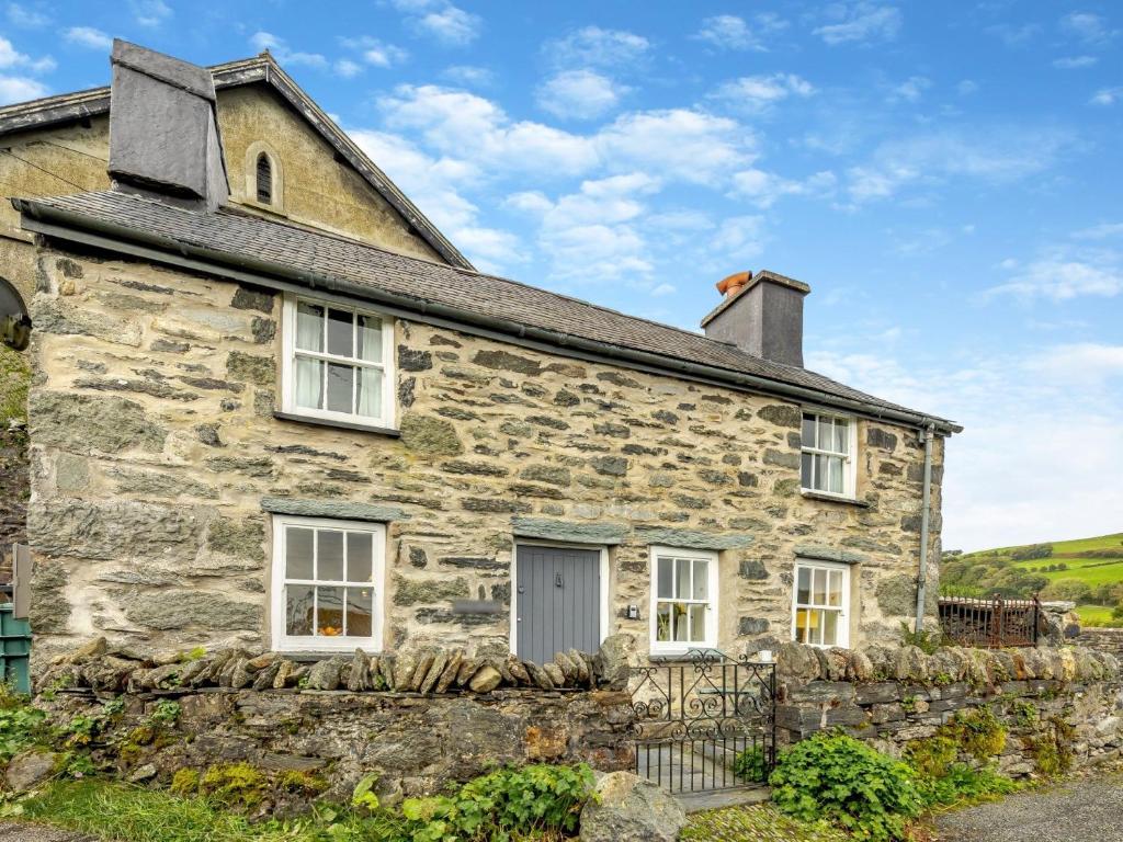una vecchia casa in pietra con un muro di pietra di 2 Bed in Betws-y-Coed SKN03 a Yspytty-Ifan