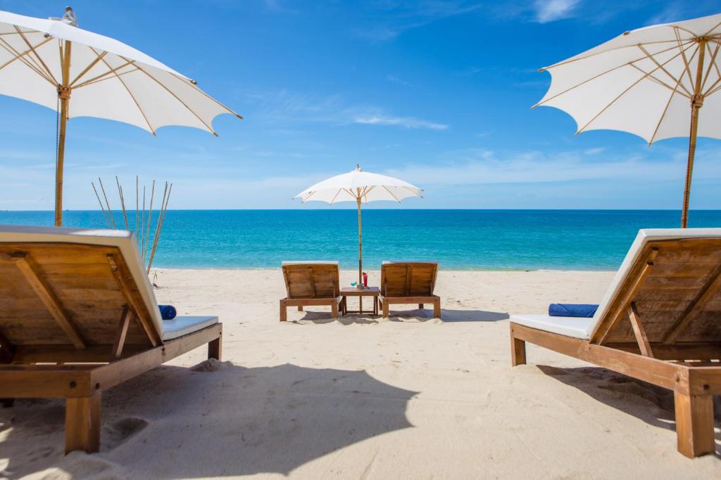 zwei Liegestühle und Sonnenschirme am Strand in der Unterkunft Lamai Coconut Beach Resort in Lamai