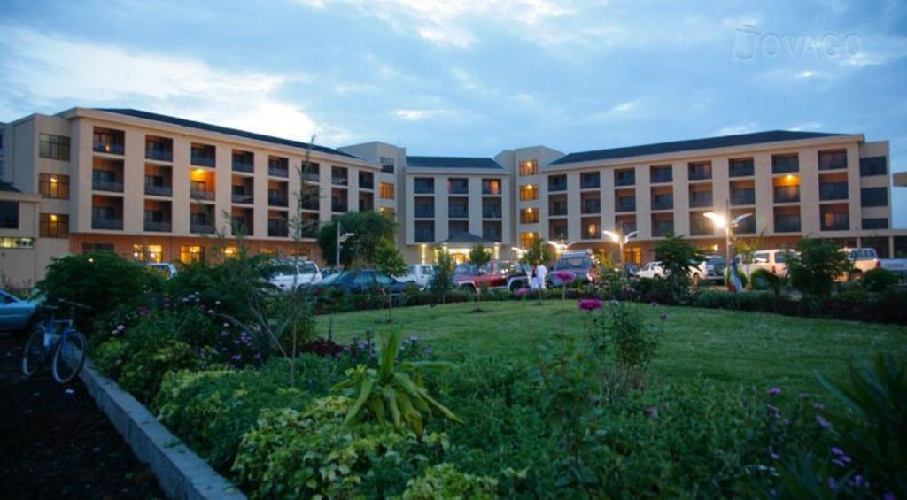 un grand bâtiment avec des voitures garées dans un parking dans l'établissement Haile Resort Hawassa, à Awasa