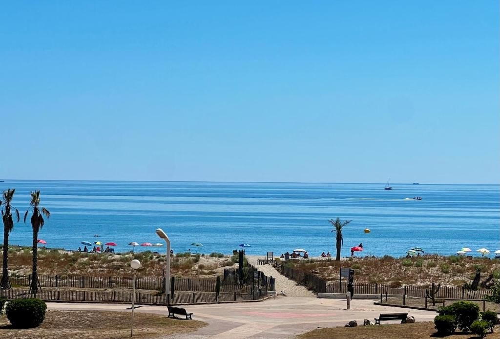 a beach with umbrellas and people on the beach at Vue mer wifi parking gratuit plage in Le Barcarès