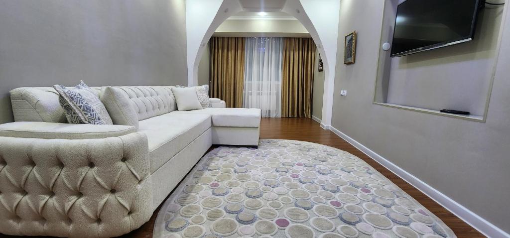 Una sala de estar con un sofá blanco y un televisor. en Independence Square Apartment, en Tashkent