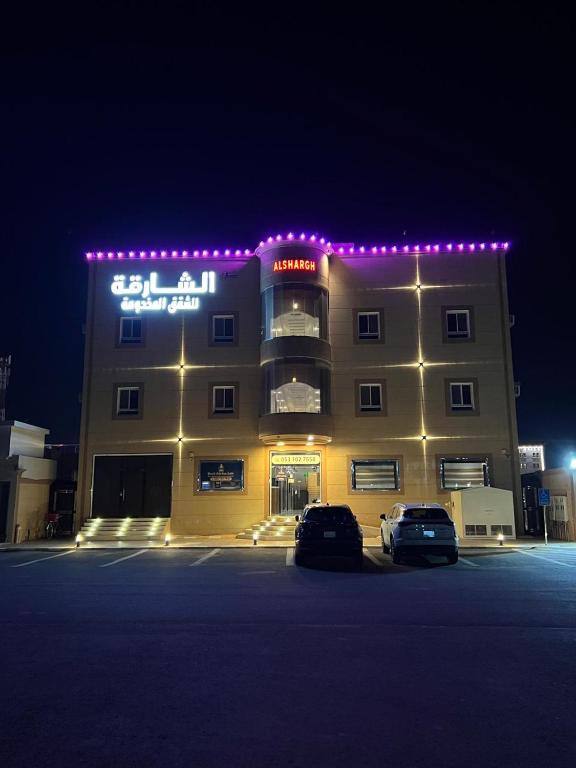a building with cars parked in a parking lot at night at برج الشارقة للشقق المخدومة in Najran