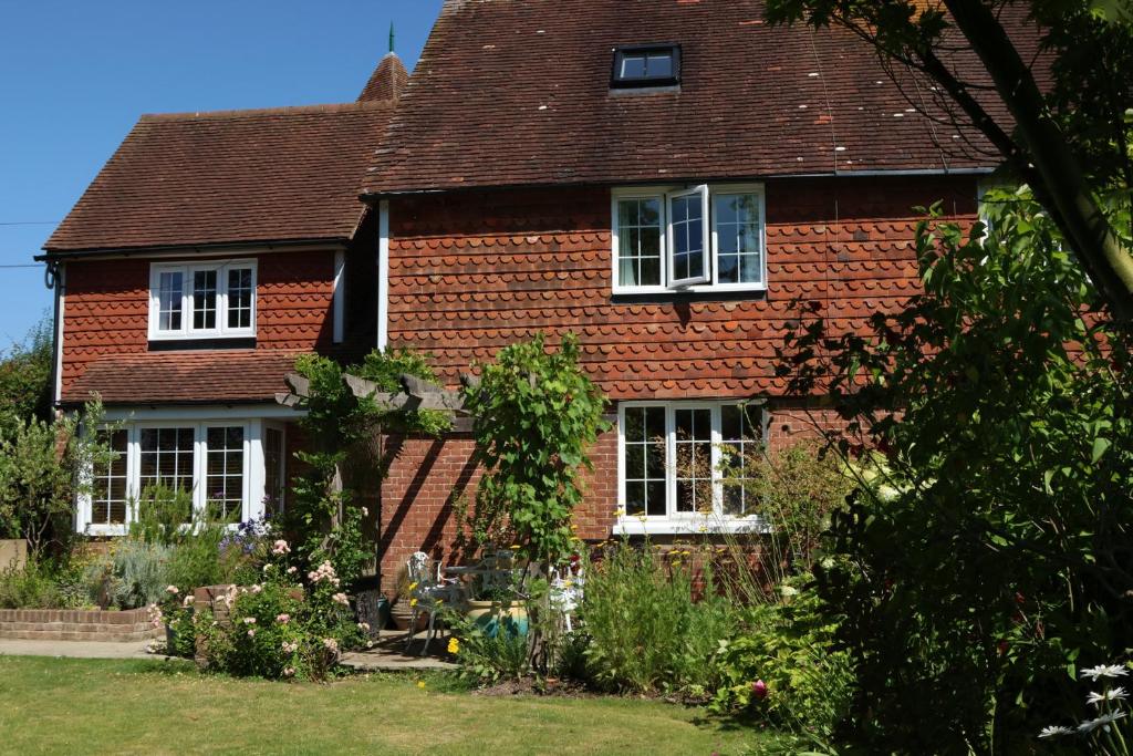 een rood bakstenen huis met witte ramen en een tuin bij Cherry Garden Cottage in Cranbrook