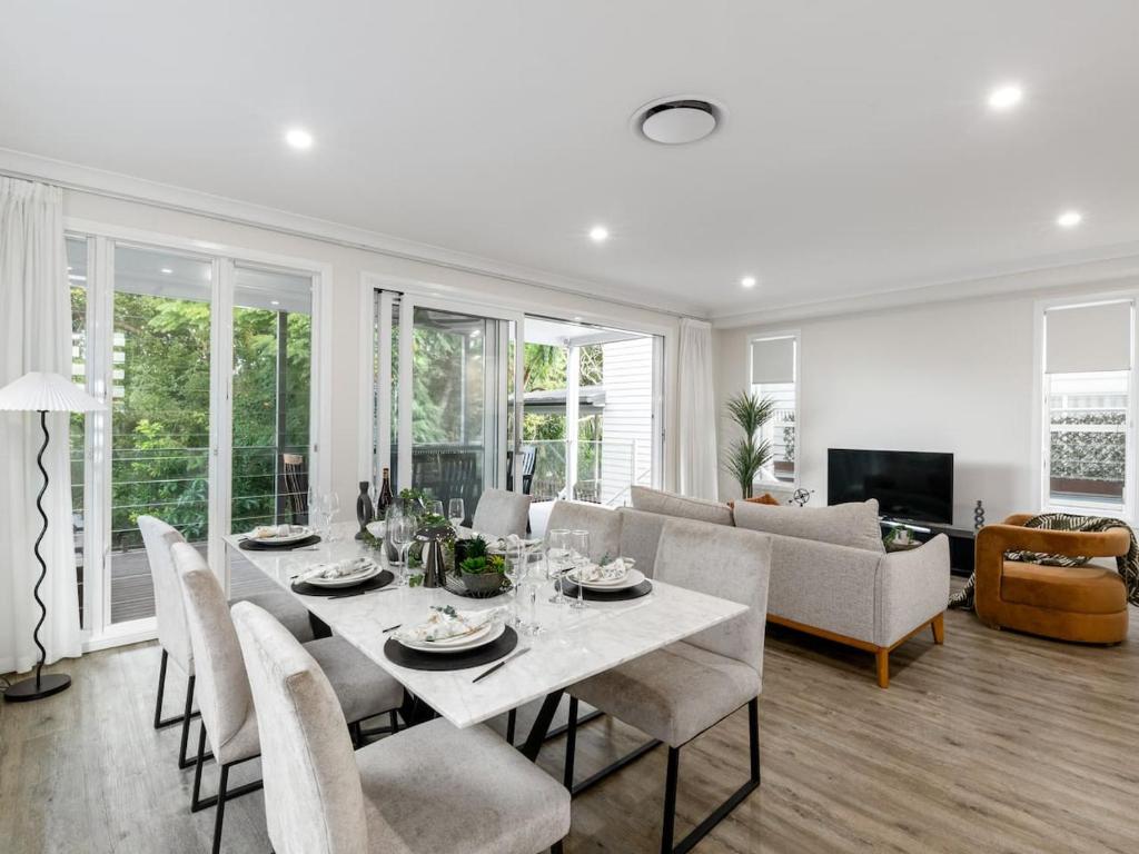 a white dining room with a table and chairs at Spacious 4-Bedroom Bardon Retreat Across 2 Levels in Brisbane