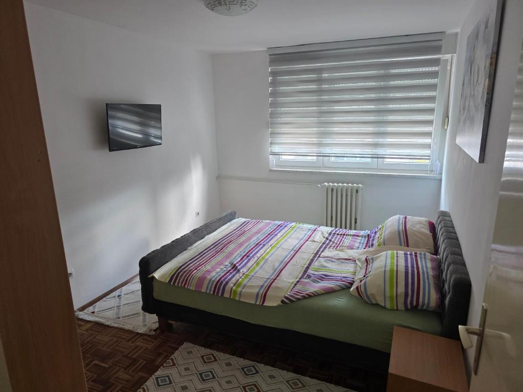 a small bed in a room with a window at Apartman BELLA in Doboj
