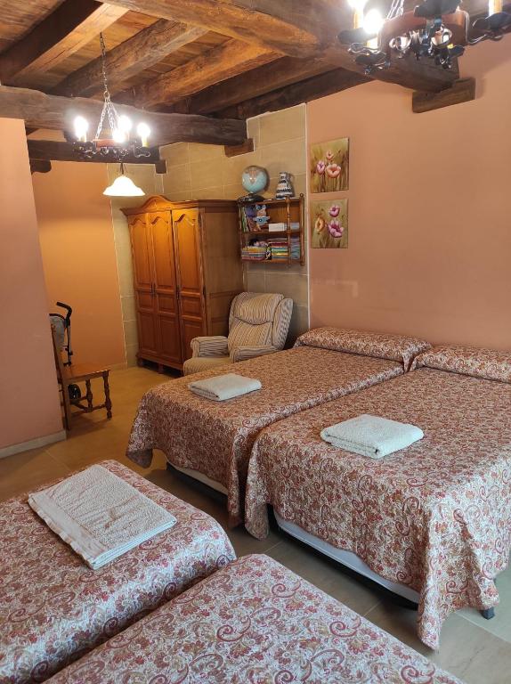 a room with three beds and a chair at Sagardikoetxea HABITACIONES CON BAÑO EN CASA RURAL in Oskotz