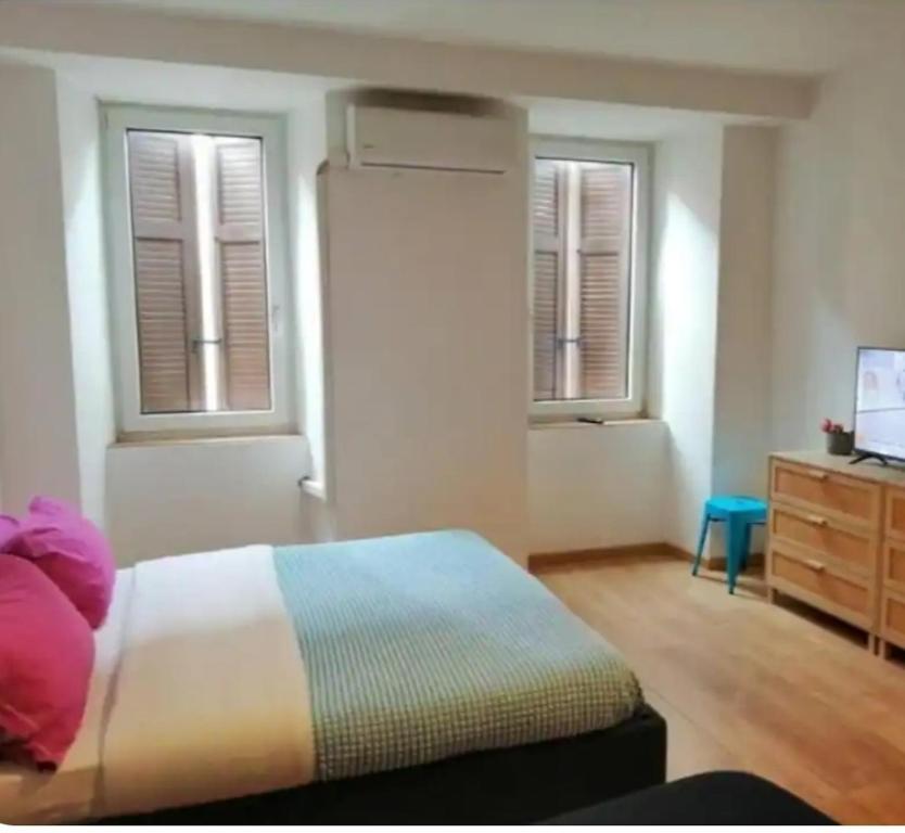 a bedroom with a bed and a dresser and two windows at lucia haus trieste in Trieste