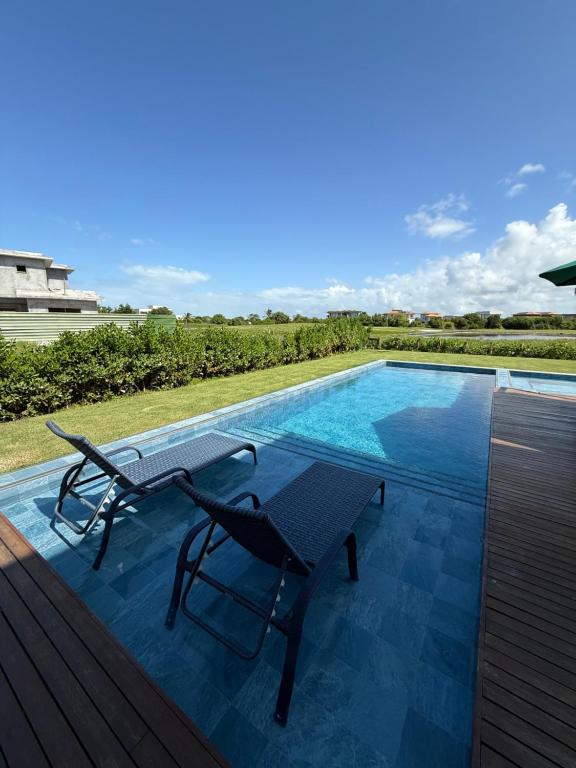 a patio with a table and chairs next to a swimming pool at Casa Temporada Praia do Forte, Complexo Iberostate, 5 Suítes in Praia do Forte
