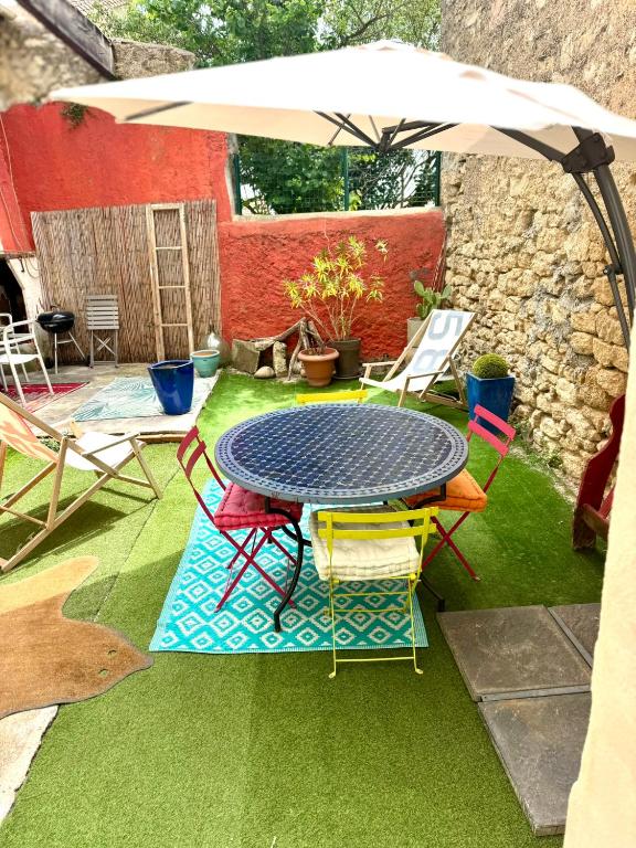un patio avec une table, des chaises et un parasol dans l'établissement VIGNERONNE VILLAGE avec PATIO, à Maureilhan-et-Raméjan