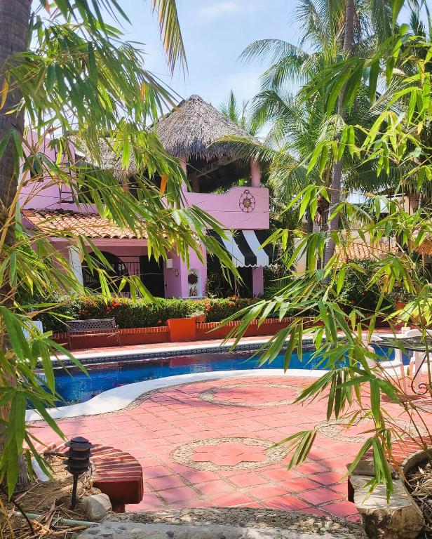 a resort with a swimming pool and palm trees at Casa Rosa Paradise in Puerto Escondido