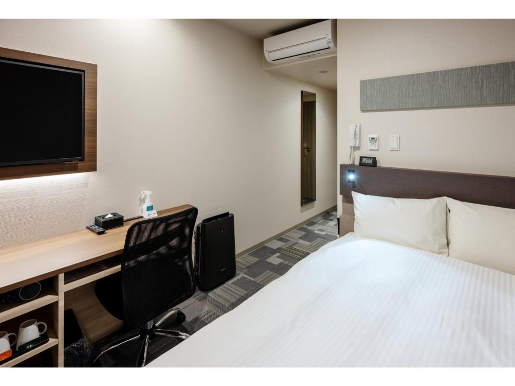 a hotel room with a bed and a desk with a tv at Smile Hotel Okayama - Vacation STAY 60155v in Okayama