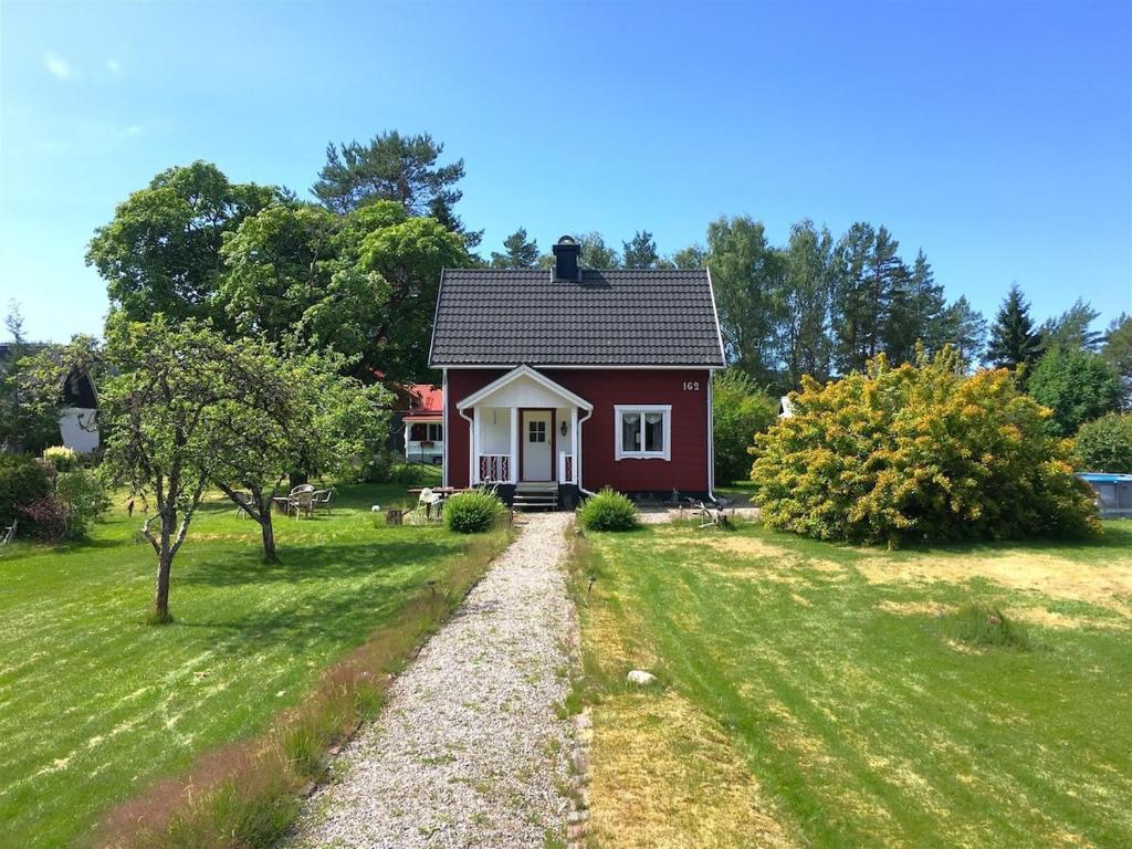 a red and white house in a grassy yard at RiverNest Bergsäng- Natur- Ruhe- Abenteuer in Bergsäng