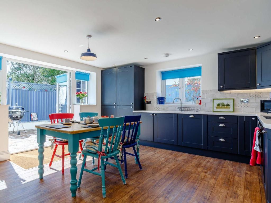a kitchen with blue cabinets and a table and chairs at 2 bed in Week St Mary 82455 in Week Saint Mary