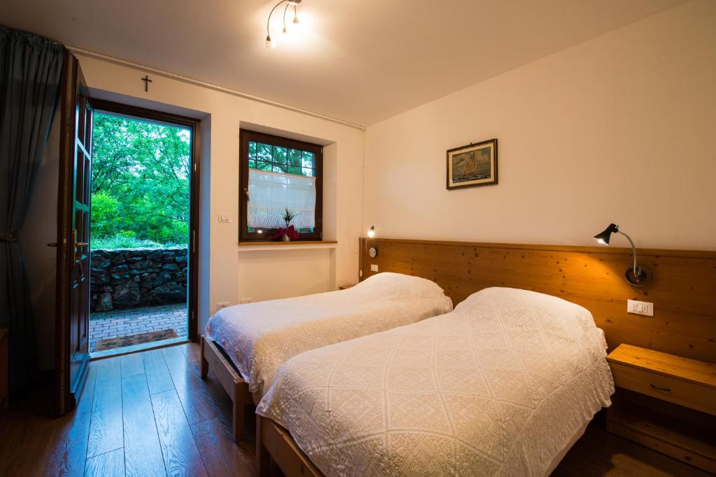 2 łóżka w sypialni z oknem w obiekcie Bajta Fattoria Carsica w mieście Baita