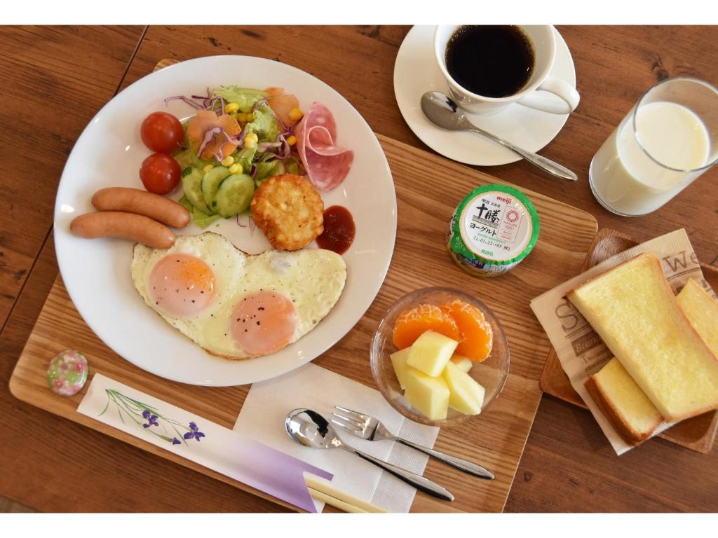 a table with a plate of breakfast food and a cup of coffee at Hotel Hanafuji Inn - Vacation STAY 82519v in Nakafurano