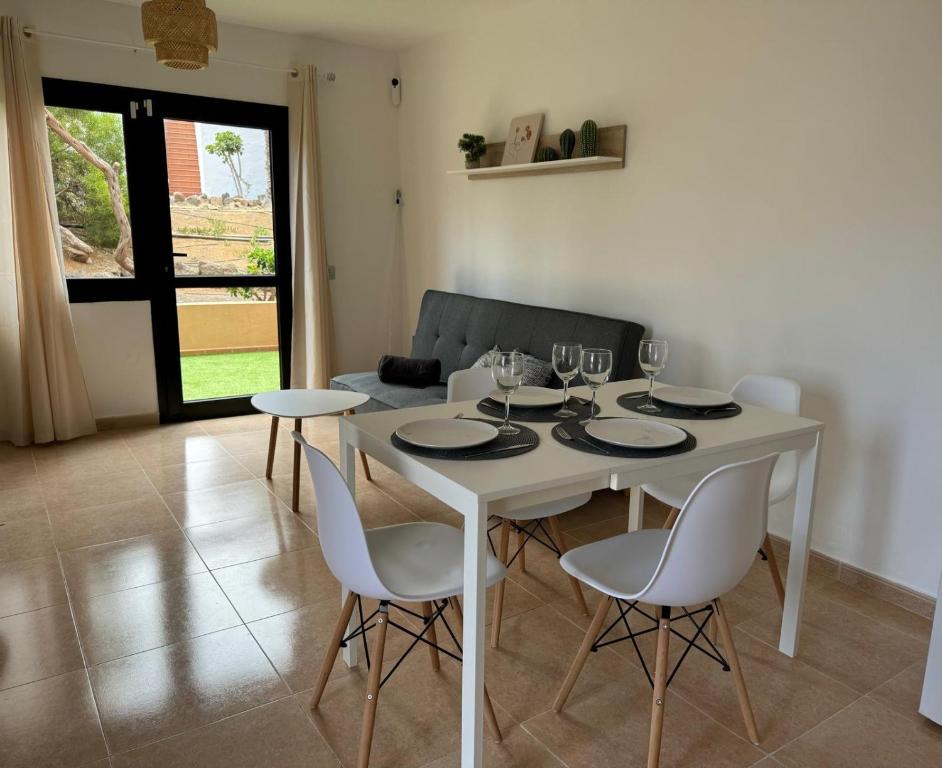 Un comedor con una mesa y sillas blancas. en Casa Olivia Oasis Duna, en Corralejo